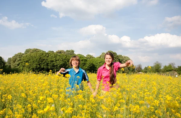 女の子と男の子の黄色の花でいっぱいの草原でリラックス ソフト フォーカス 目に焦点を当てる — ストック写真