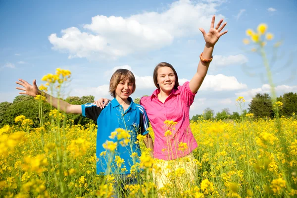 女の子と男の子の黄色の花でいっぱいの草原でリラックス。柔らかい foc — ストック写真