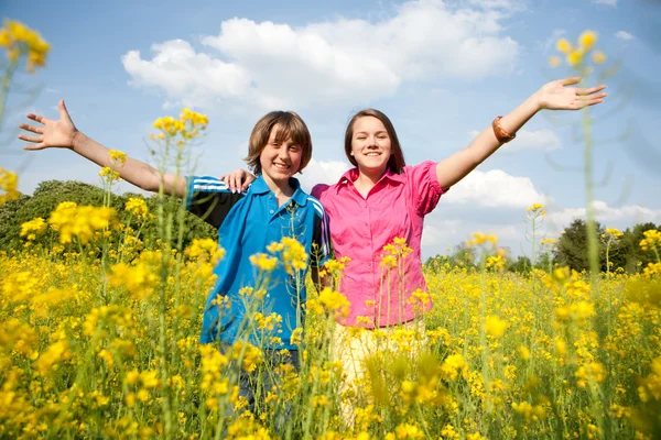 Menina e menino relaxando no prado cheio de flores amarelas. Suave foc — Fotografia de Stock