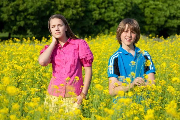 Dziewczyna i chłopak się łąka pełna kwiatów żółty. miękkie foc — Zdjęcie stockowe