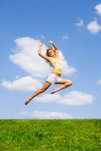 Happy young woman is dancing in a field