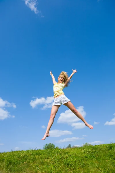 Glad ung kvinna hoppar i ett fält — Stockfoto
