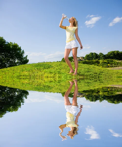 Mooi meisje drinkwater tegen blauwe hemel — Stockfoto