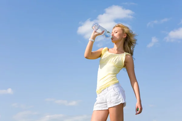 Krásná dívka pitné vody proti modré obloze 2 — Stock fotografie
