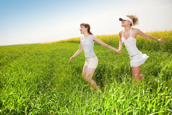 Two happy young women are runing in a field — Stock Photo, Image