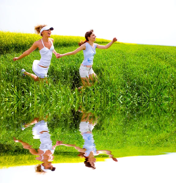 Две счастливые молодые женщины бегут в поле — стоковое фото