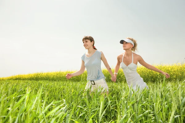 Дві молоді дівчата щасливо стрибають на траві — стокове фото