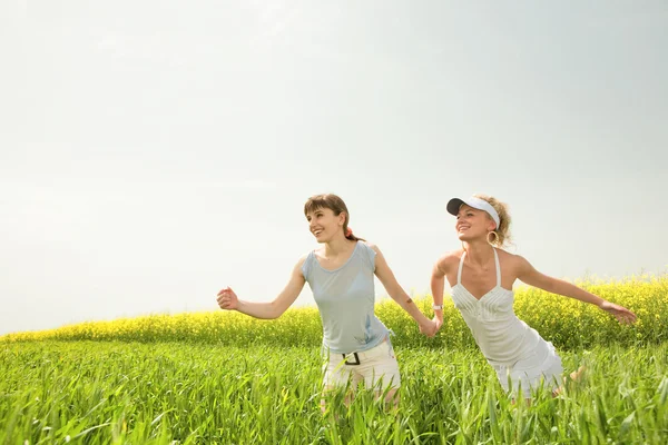 Dos chicas jóvenes están felizmente saltando sobre la hierba — Foto de Stock