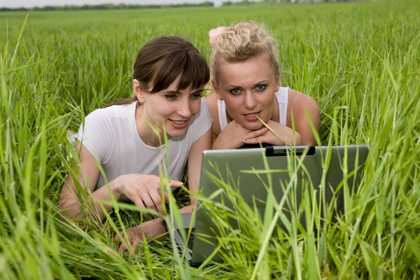 Due belle ragazze in vestiti bianchi stanno ridendo vicino al computer portatile co — Foto Stock