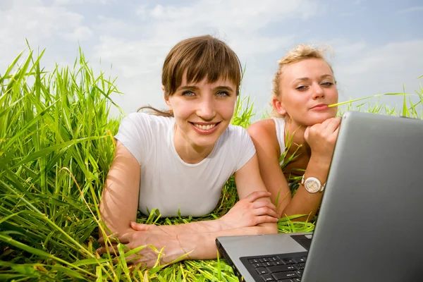 Duas meninas bonitas em roupas brancas estão rindo perto do laptop co — Fotografia de Stock