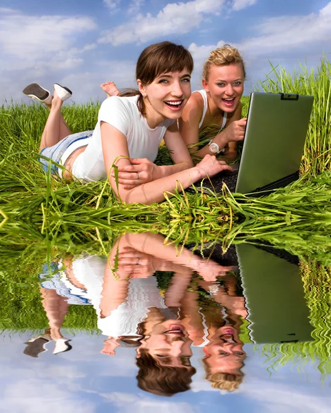Two beautiful girls in white clothes are laughing near laptop co — Stock Photo, Image