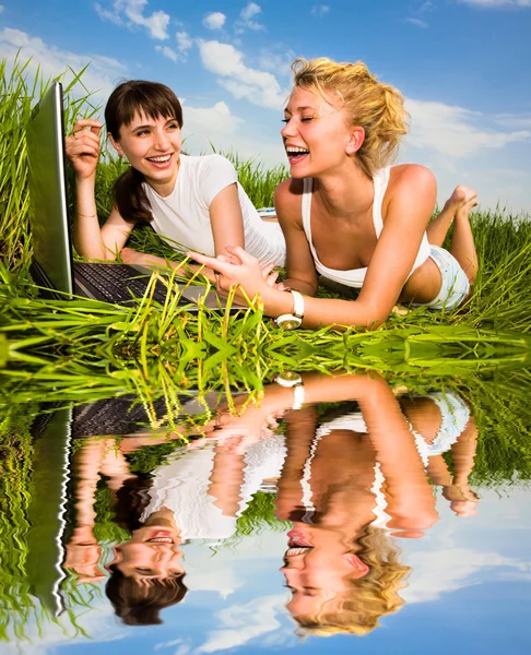 Two beautiful girl in white clothes on a laptop computer outdoor — Stock Photo, Image