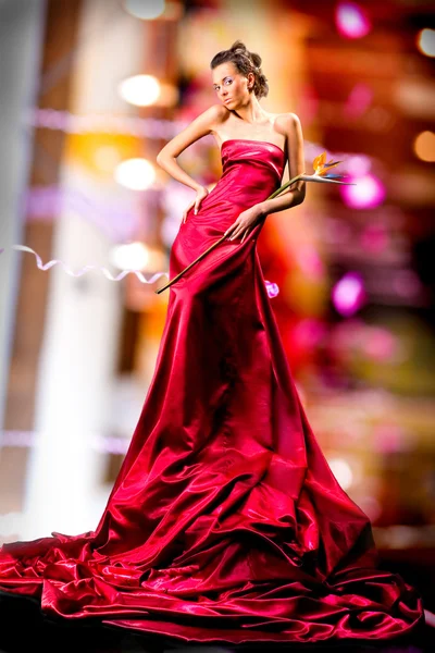 長い赤いドレスで美しい少女をエキゾチックな花を手に保持します — ストック写真