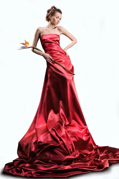 長い赤いドレスで美しい少女白い背景の上の手で エキゾチックな花を保持します — ストック写真