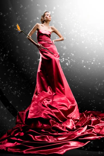Gyönyörű lány, hosszú piros ruhás tart egzotikus virág a kézben — Stock Fotó