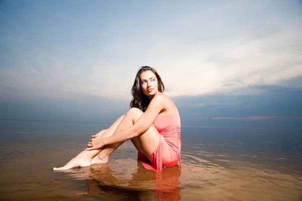 Krásná dívka sedící na vodě — Stock fotografie