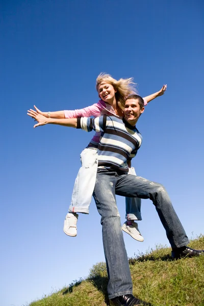 Glad ung kärlek par - hoppning under blå himmel — Stockfoto