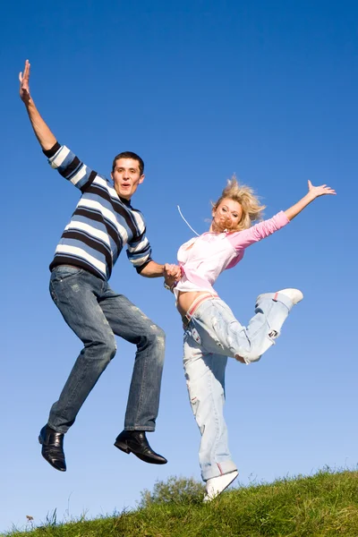 Счастливая молодая влюбленная пара - прыжки под синим небом — стоковое фото