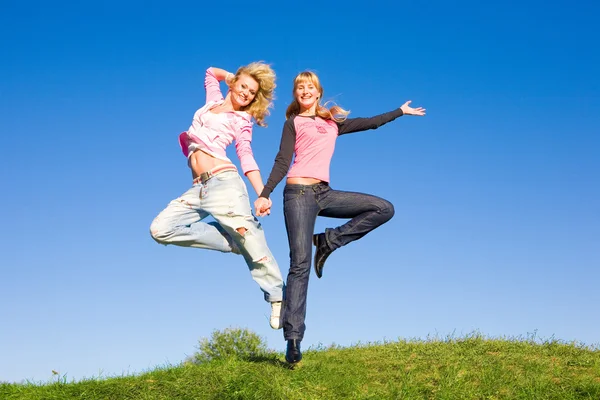 两个快乐的女孩在绿色的草地上跳跃 — 图库照片