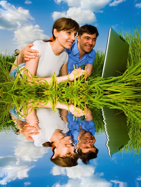 Casual happy couple on a laptop computer outdoors. Lay on the gr — Stock Photo, Image