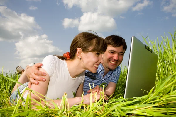Casual casal feliz no computador portátil ao ar livre. Deite-se no gree — Fotografia de Stock