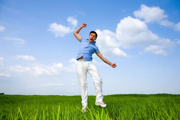 Homem feliz está pulando em um campo — Fotografia de Stock