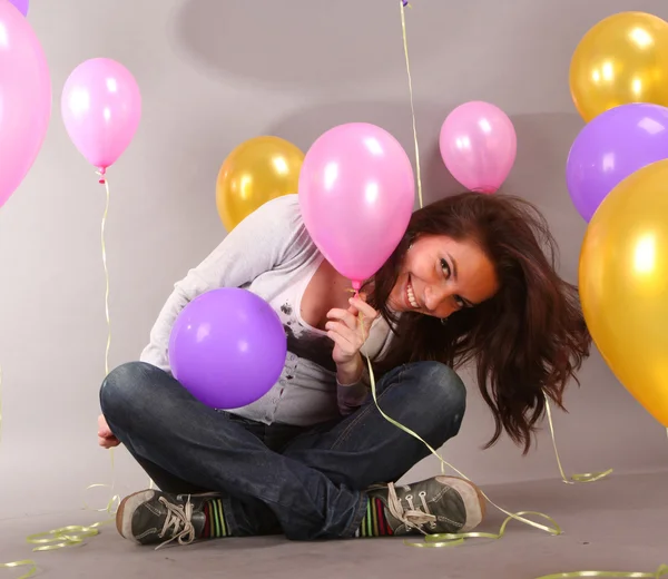 Happy beautiful young woman smiles at background balloons — Stock Photo, Image