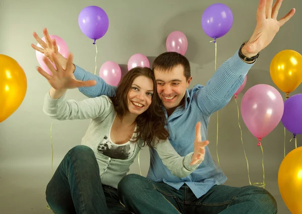 Молода любов пара посміхається з повітряними кулями — стокове фото
