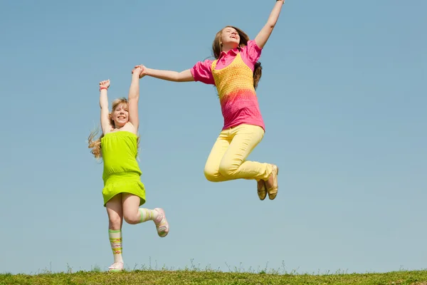 Dwie dziewczyny skoki na zielony łąka — Zdjęcie stockowe