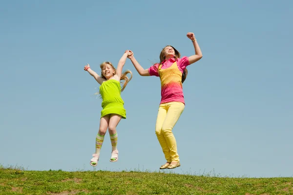 Dos chicas saltando en el prado verde — Foto de Stock