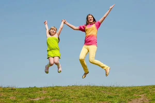 Две Девушки Прыгают Зеленому Лугу — стоковое фото