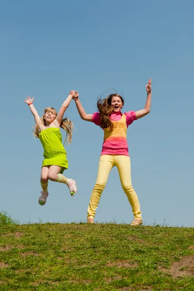 Två flickor hoppa på grön äng — Stockfoto