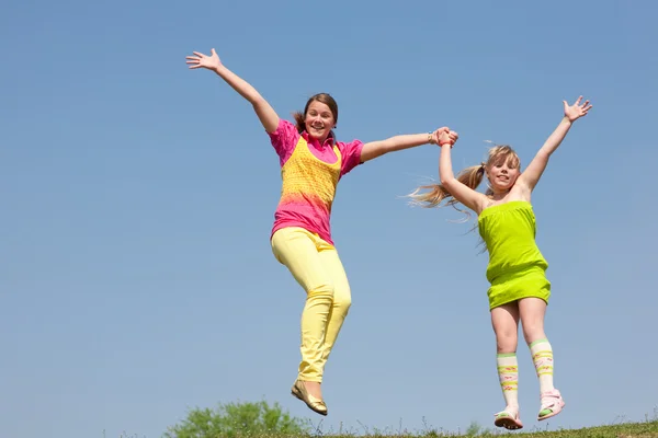 Zwei Mädchen springen auf grüne Wiese — Stockfoto