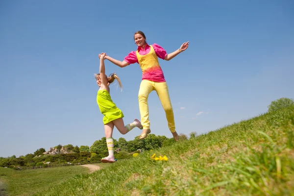 Deux filles sautant sur la prairie verte — Photo
