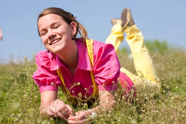 漂亮微笑女孩充满鲜花的绿色草地上放松 软焦点 把重点放在眼睛上 — 图库照片
