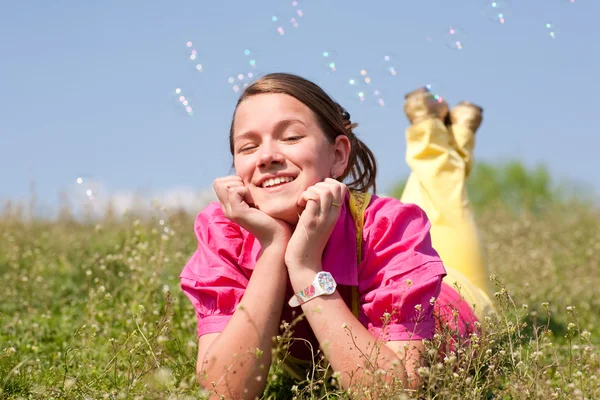 Jolie fille souriante se détendre sur une prairie verte pleine de fleurs. Alors... — Photo