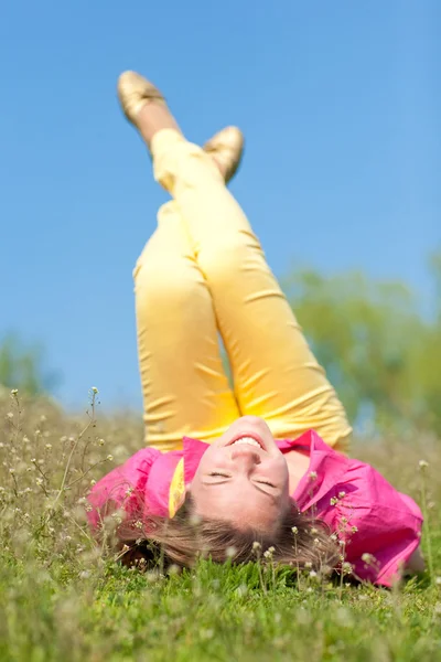 Vrij lachende meisje ontspannen op groene weide vol met bloemen. dus — Stockfoto