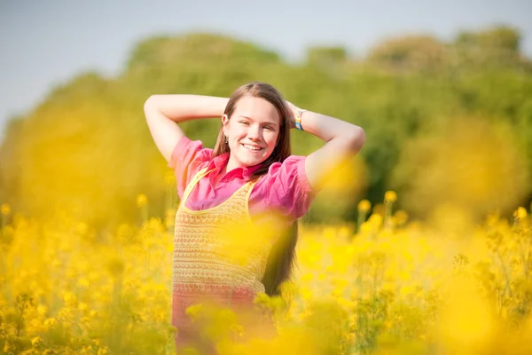 Hübsches lächelndes Mädchen entspannt sich auf einer grünen Wiese voller gelber Strömung — Stockfoto