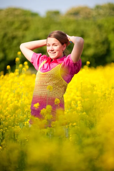 Досить усміхнена дівчина розслабляється на зеленому лузі, повній квітів. Отже — стокове фото