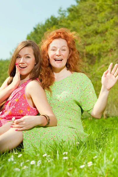 Смішна мати і дочка сидять на зеленій траві — стокове фото