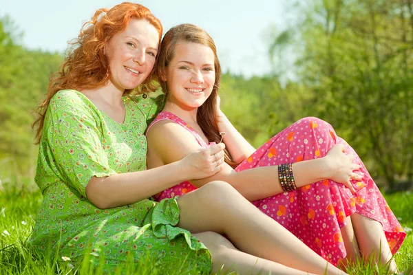 Divertida madre e hija sentado en la hierba verde —  Fotos de Stock