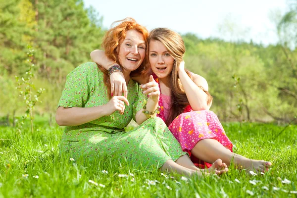 有趣的母亲和女儿坐在绿草地上 — 图库照片