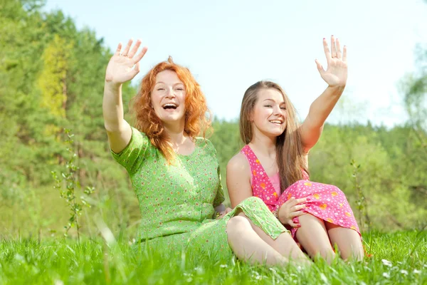 Funny mother and daughter sitting on green grass — Stock Photo, Image