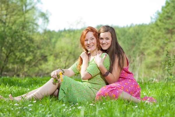 Legrační matka a dcera sedí na zelené trávě — Stock fotografie
