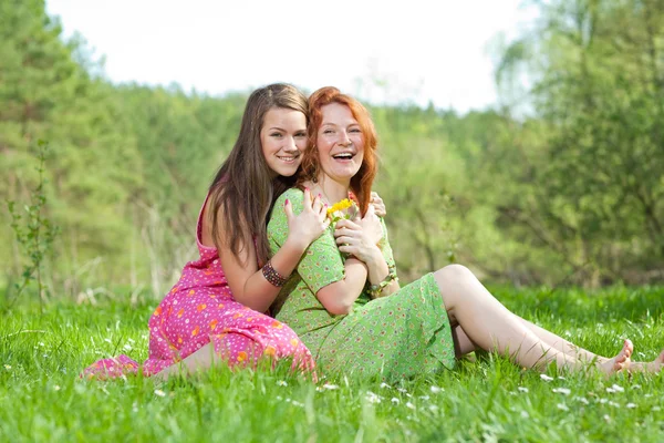 Funny mother and daughter sitting on green grass — Stock Photo, Image