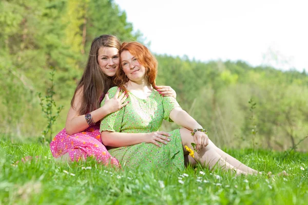 有趣的母亲和女儿坐在绿草地上 — 图库照片