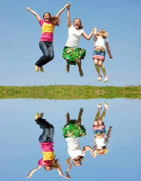 ハッピーママと緑の草原にジャンプ つの娘 — ストック写真