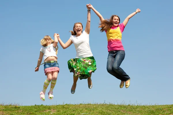 stock image Happy Mom and two daughter jumping on green meadow