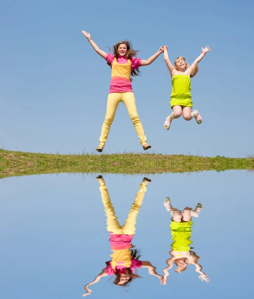 Deux filles sautant sur la prairie verte — Photo
