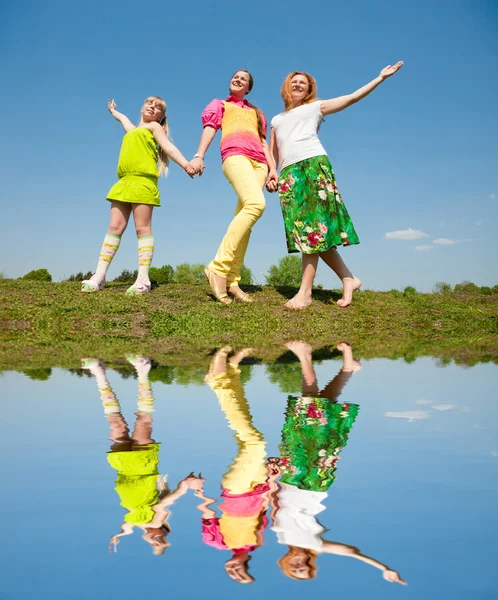 母亲和两个女儿在绿色草地上跳跃 — 图库照片